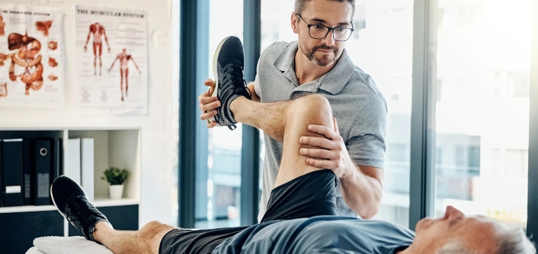 Physiotherapist stretching out a man's leg.