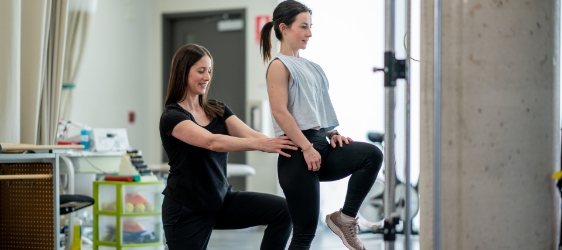 Physiotherapist assisting a patient with a step-up exercise in a rehabilitation clinic.