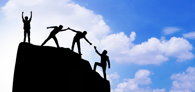 Silhouettes of people helping each other up a hill
